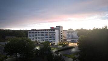 A Marriott hotel with a modern design, featuring a large building with multiple floors and a prominent sign. The hotel is surrounded by greenery and has a parking lot in front.