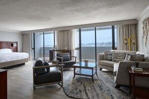 Una habitación de hotel moderna con una cama grande, dos sofás, una mesa de centro y vistas a la ciudad.