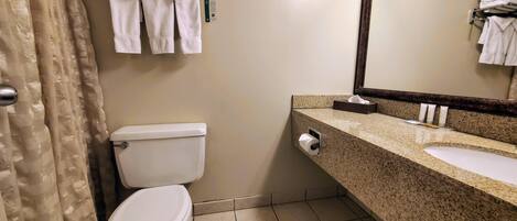 A bathroom with a toilet, a sink, a mirror, and a towel rack with folded towels.