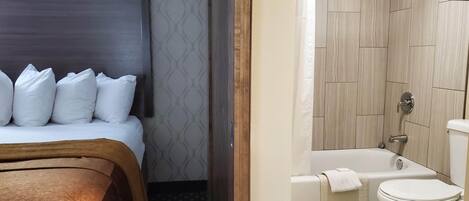 A hotel room with a bed, a shower, and a toilet.