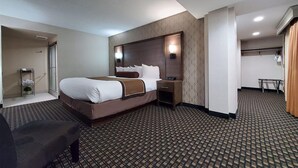 Una habitación de hotel con una cama grande, una mesita de noche y una pequeña zona de estar.