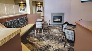 A hotel lobby with a seating area, a fireplace, and a television screen.