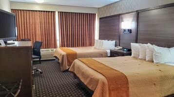 Une chambre d’hôtel avec deux lits, un bureau avec un ordinateur, une chaise et un téléviseur.
