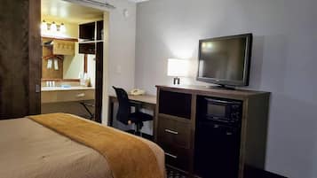 Une chambre d’hôtel comprenant un lit, un bureau avec un ordinateur, une télévision et une armoire.