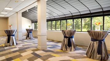 Una habitación de hotel con alfombra a cuadros, ventanas amplias y cortinas atadas con cintas.
