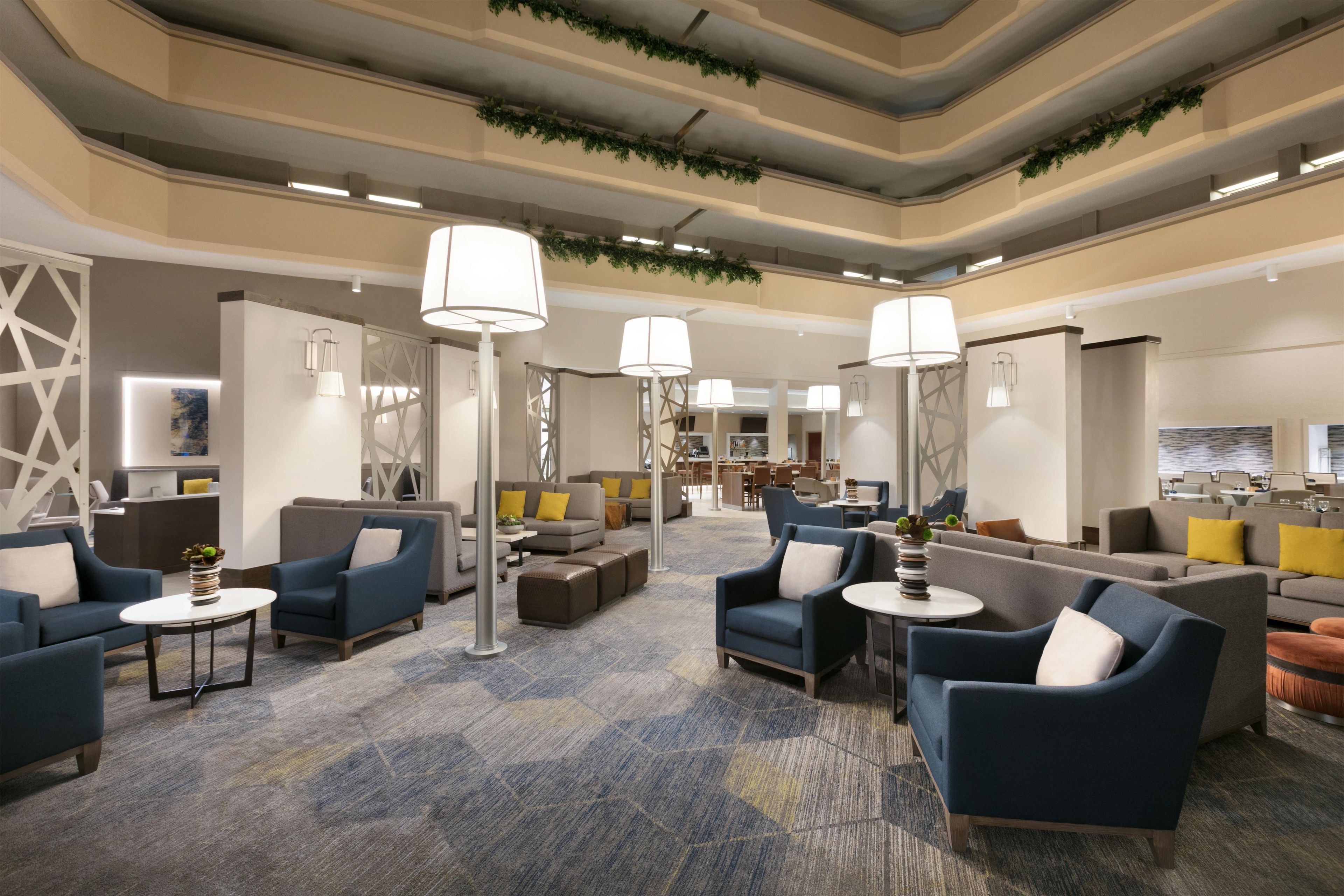 A spacious lobby with multiple seating areas, including sofas and armchairs, and a reception desk.
