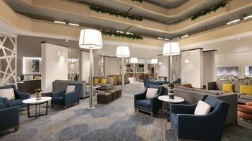 A spacious lobby with multiple seating areas, including sofas and armchairs, and a reception desk.