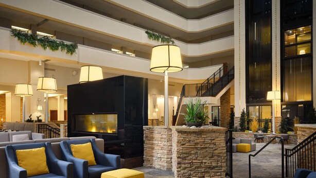 A spacious lobby with a fireplace, comfortable seating, and a staircase leading to upper floors. - Hilton Fort Collins (Fort Collins)