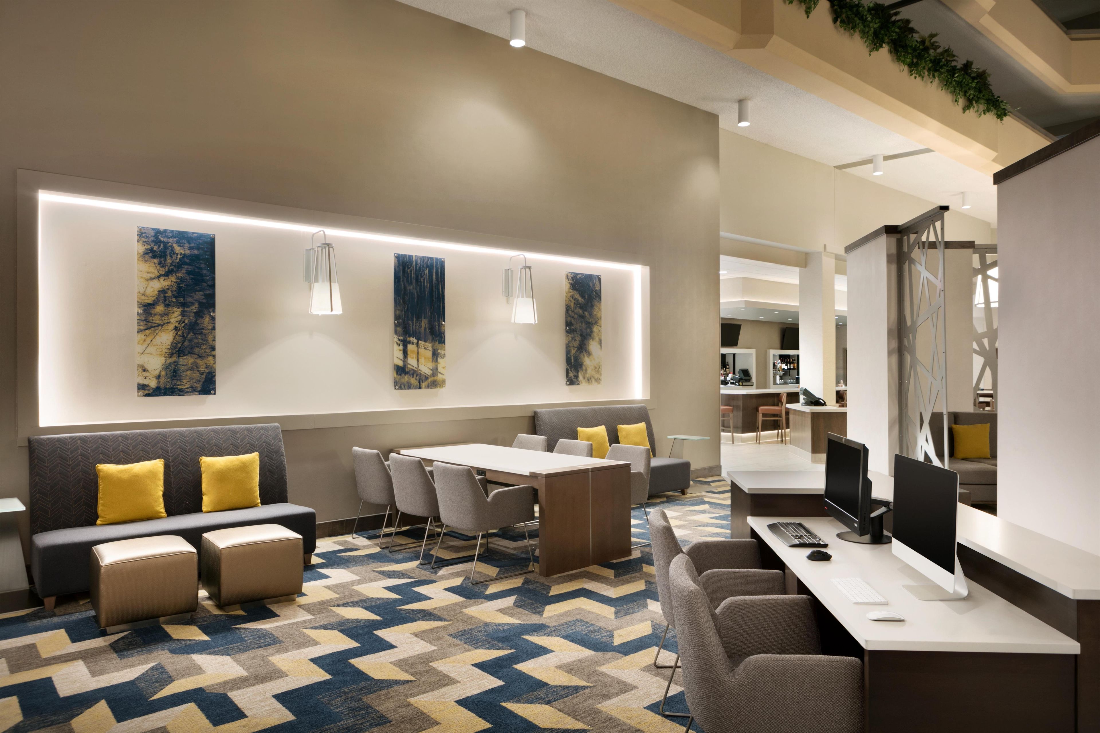 Un hall d’hôtel moderne avec un comptoir d’accueil, un espace salon et des œuvres d’art accrochées aux murs.