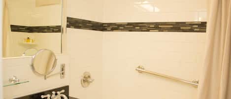 Un baño con lavamanos blanco, espejo y ducha.