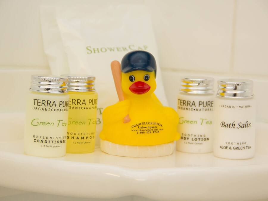 Een badkamerplank met Terra Pure shampoo, conditioner en badzout, een rubberen eend en een douchemuts.