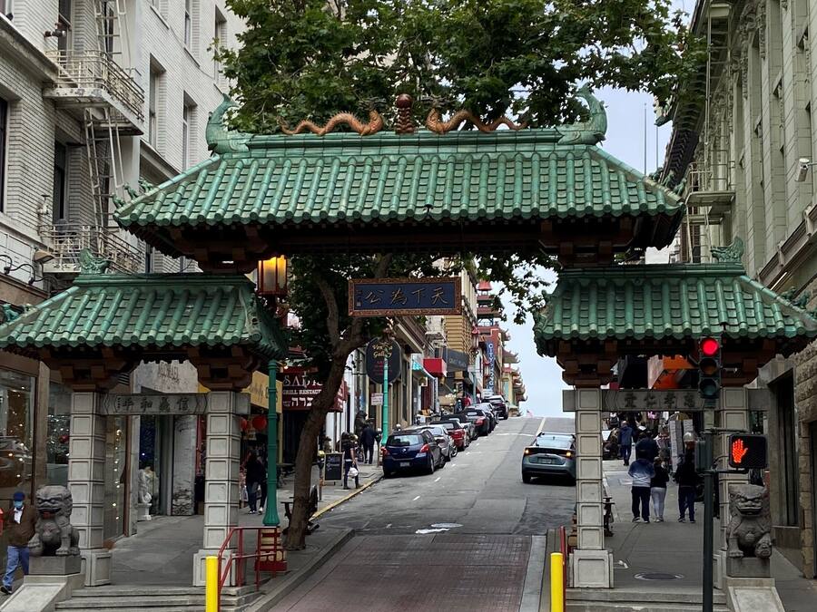 A street with traditional Chinese architecture, including a gate with dragons and a pagoda-style roof.