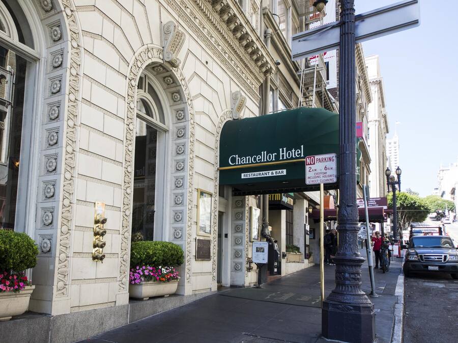 The exterior of the Chancellor Hotel with a green awning, a 'No Parking' sign, and a 'Restaurant & Bar' sign.