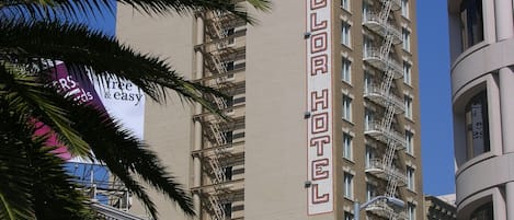 Um hotel alto com uma placa visível, várias varandas e um estilo arquitetônico clássico.