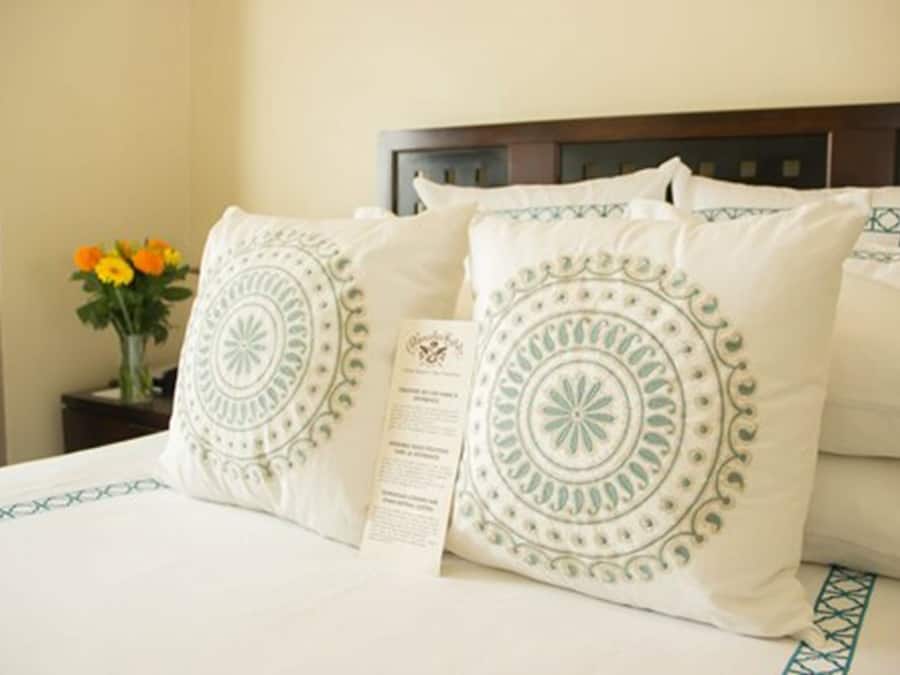A neatly made bed with white bedding and decorative pillows featuring circular patterns.