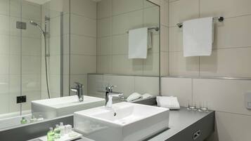 A modern bathroom with two sinks, a shower, and a large mirror.