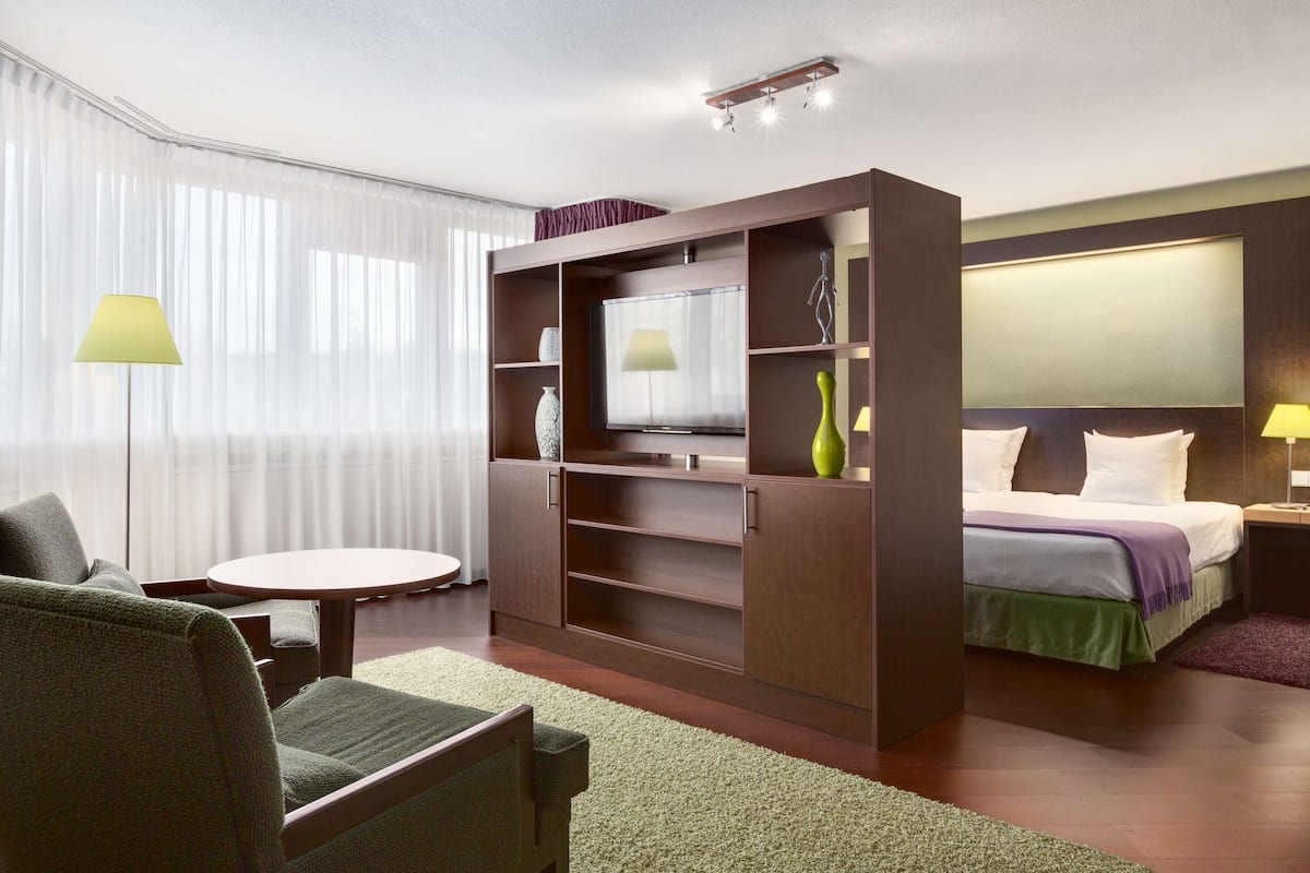 A modern hotel room with a large bed, a desk, a sofa, and a TV.