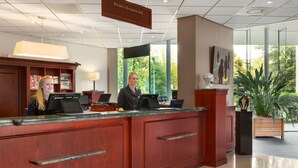 A reception desk with a receptionist, a computer, and a sign indicating the reception area. - NH Maastricht (Maastricht)
