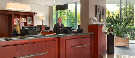 A reception desk with a receptionist, a computer, and a sign indicating the reception area.