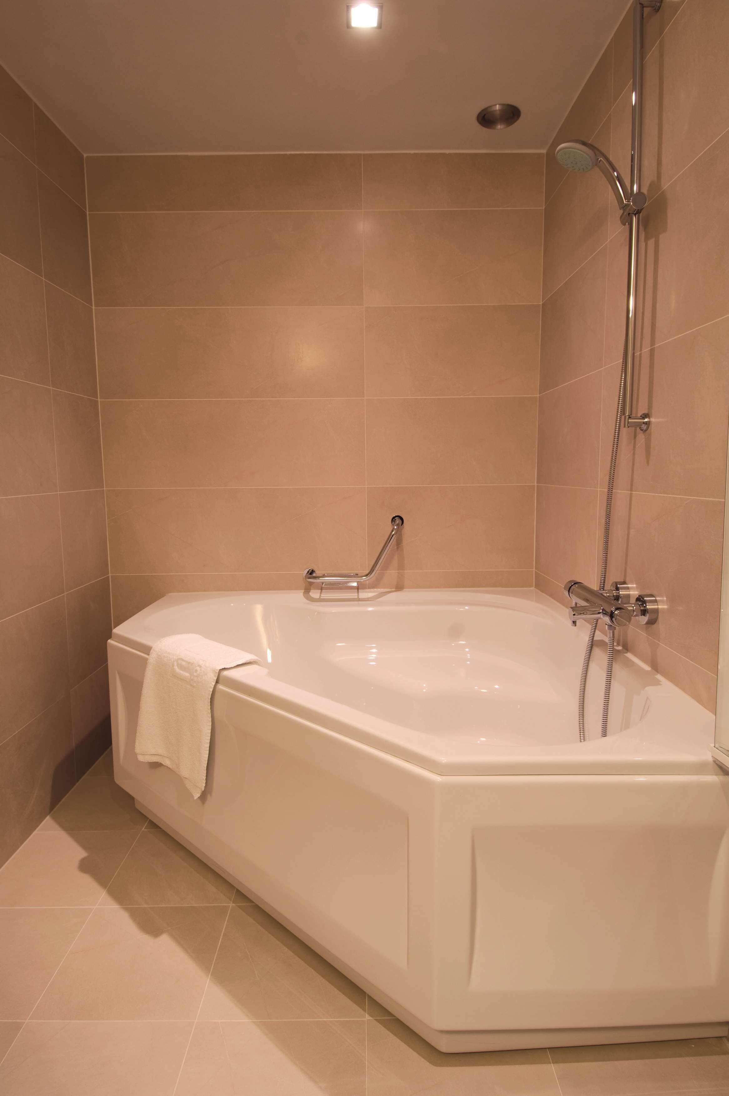 Ein modernes Badezimmer mit einer großen Badewanne, einer Duschbrause und einem Handtuchhalter.