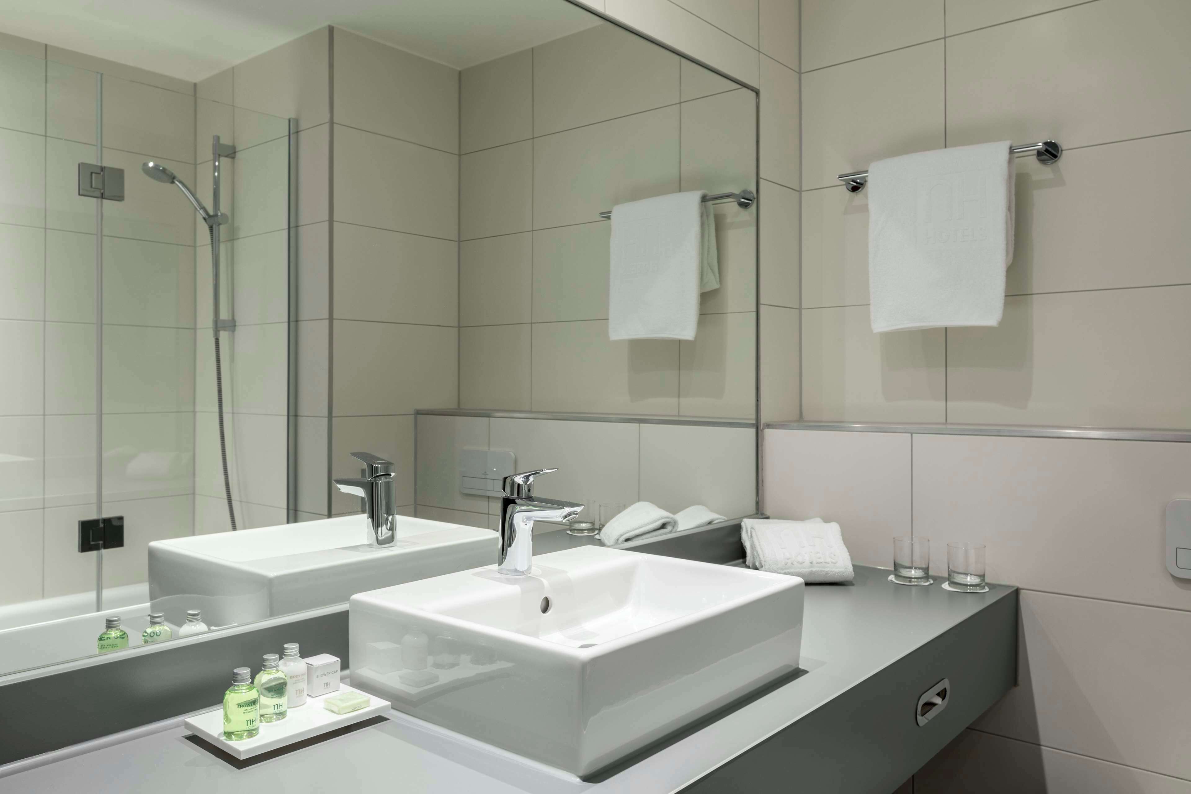 Une salle de bain moderne avec deux lavabos, une douche à l’italienne en verre et un grand miroir.