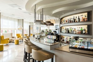 A modern bar area with a curved counter, bar stools, and a variety of liquor bottles. - NH Maastricht (Maastricht)