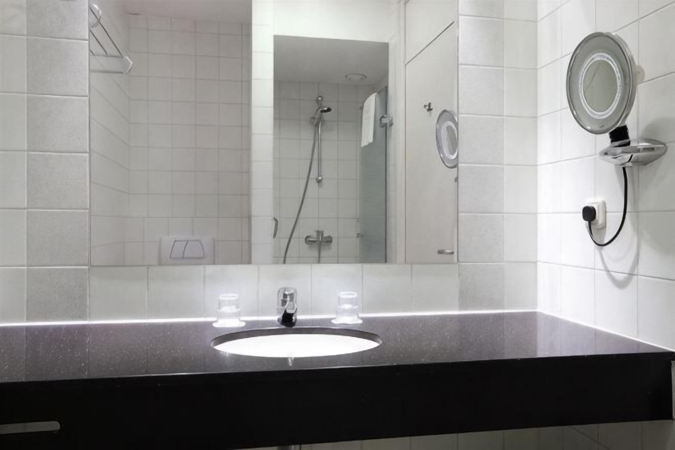 A bathroom with a sink, mirror, and shower.