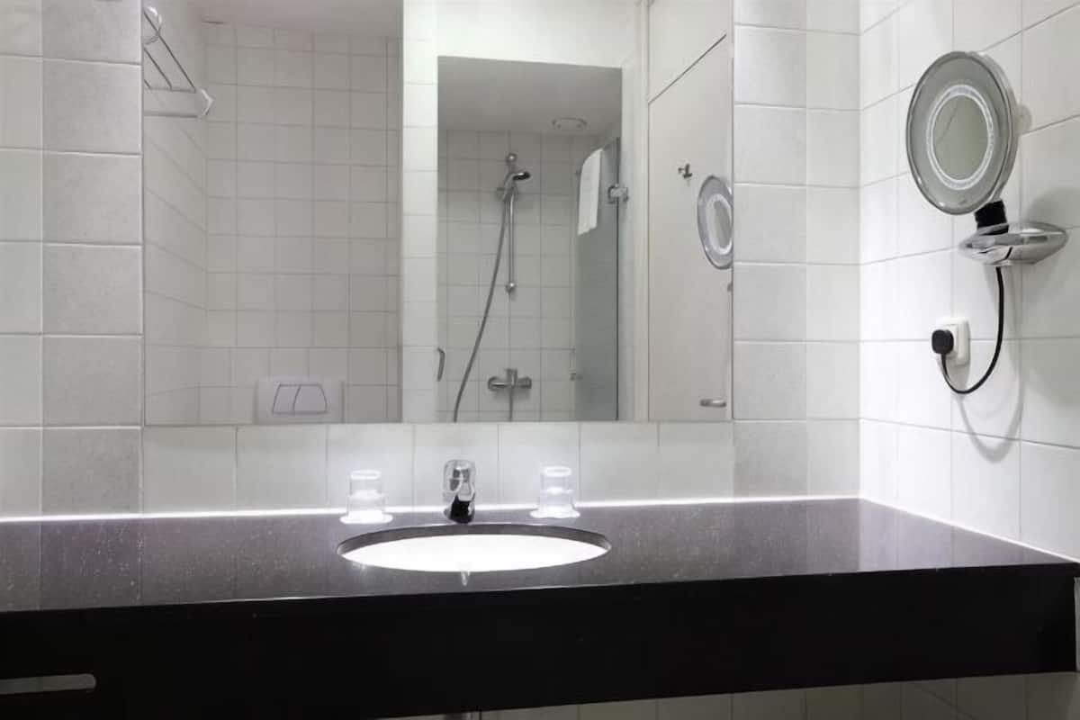 A bathroom with a sink, mirror, and shower.