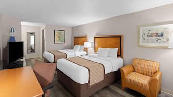 A hotel room with two beds, a TV, a desk, and a chair.