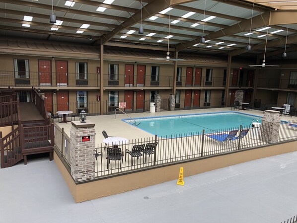 Una amplia piscina interior con zona vallada, varios balcones y una escalera que sube a un nivel superior.