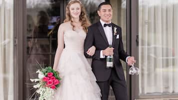 A couple in wedding attire standing in front of a Baymont Inn & Suites sign.