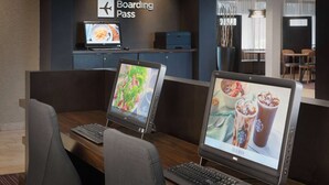 Un mostrador de recepción con un cartel que dice 'Boarding Pass', computadoras y zona de espera.