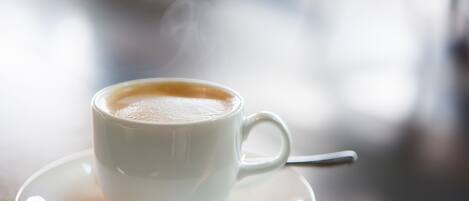 A white cup of coffee with steam on a saucer.