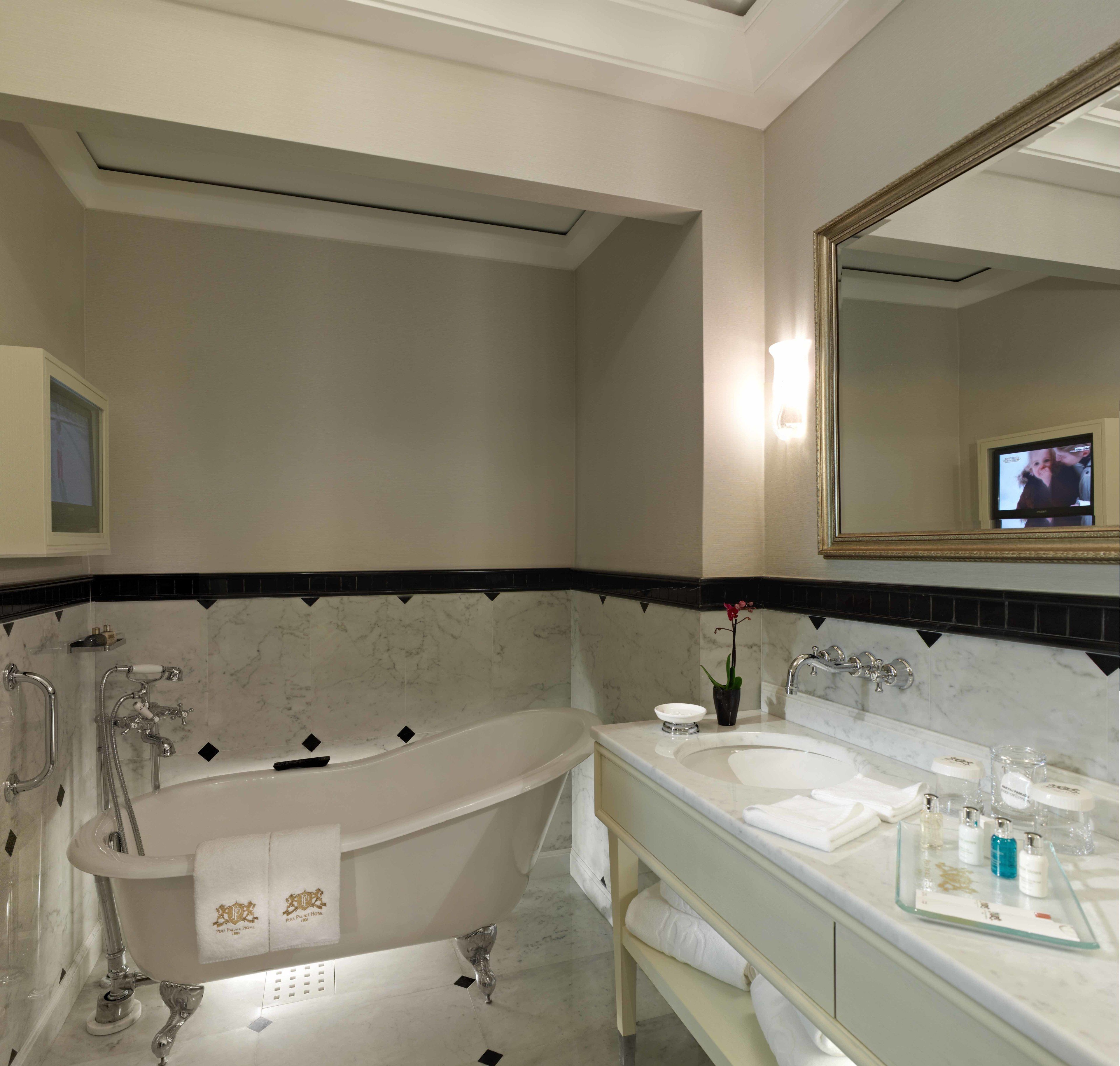 A modern bathroom with a freestanding bathtub, a large mirror, and a vanity with a glass countertop.