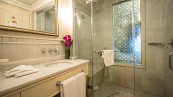 Un baño moderno con cabina de ducha de vidrio, un espejo grande y un jarrón con flores.