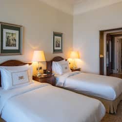 Two single beds with wooden headboards and matching nightstands, adorned with white linens and decorative pillows.