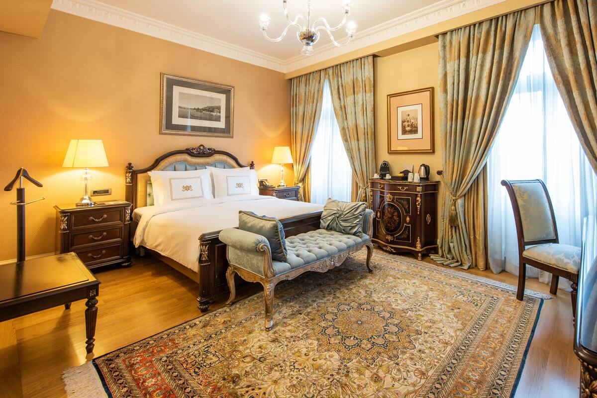 A spacious bedroom with a large bed, a sitting area, and a television.