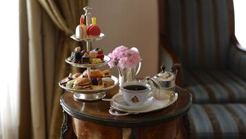 Un présentoir à trois niveaux, garni de pâtisseries, et une tasse de café, le tout posé sur une table ronde.