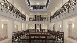 A grand interior with a central open space, ornate black railings, and a glass ceiling. - Pera Palace Hotel (Istanbul)