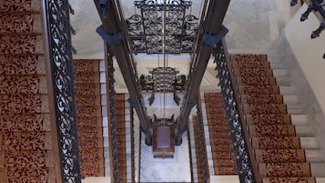 Una gran escalera con barandales de metal decorados y alfombra estampada.