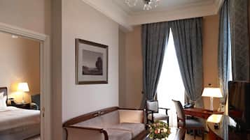 Una habitación de hotel con cama, sofá, mesa de centro, televisión y lámpara de araña.