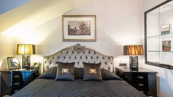 A bedroom with a tufted headboard, two bedside tables with lamps, a framed picture on the wall, and a large mirror.