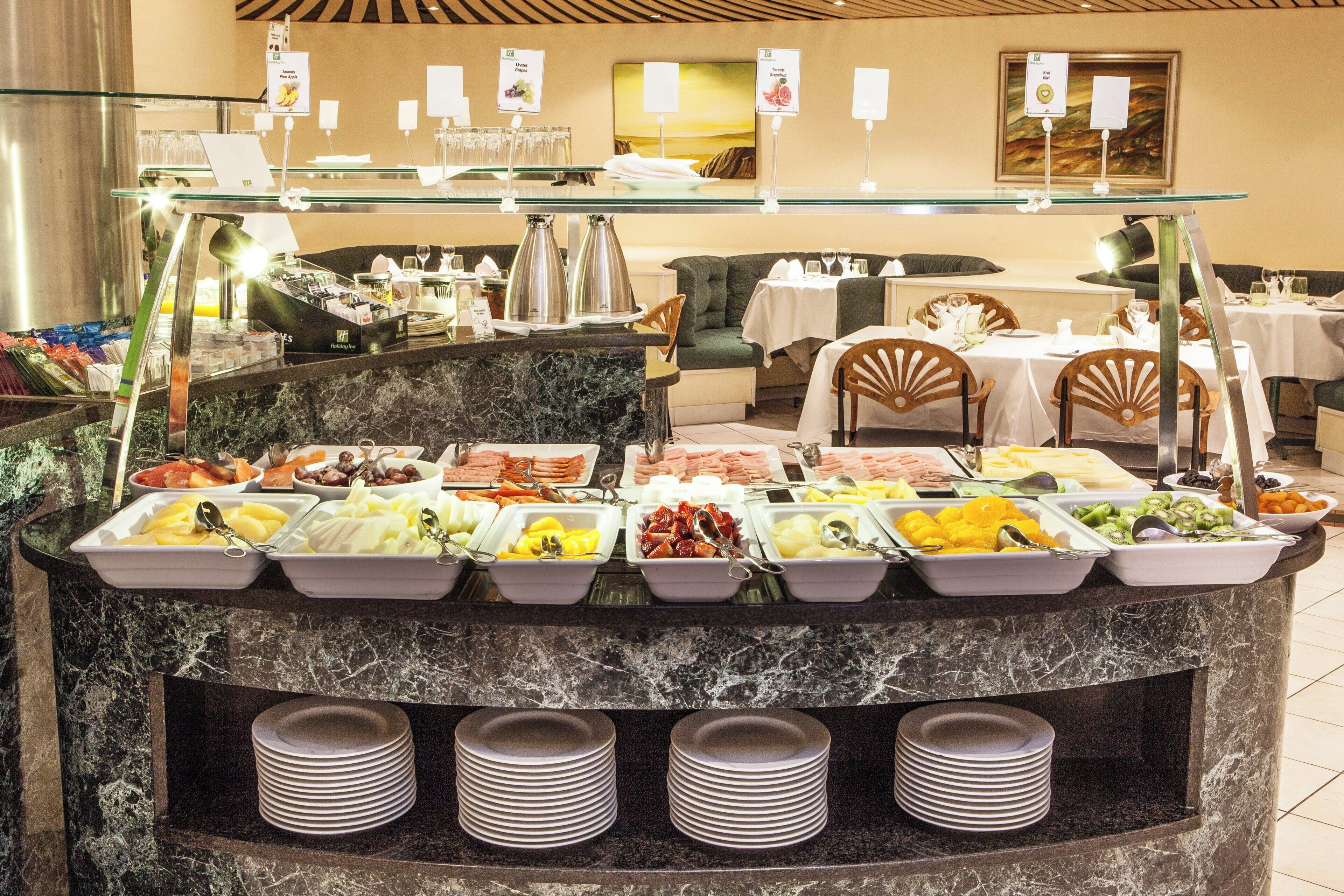A buffet area with various food options and a seating area with tables and chairs.