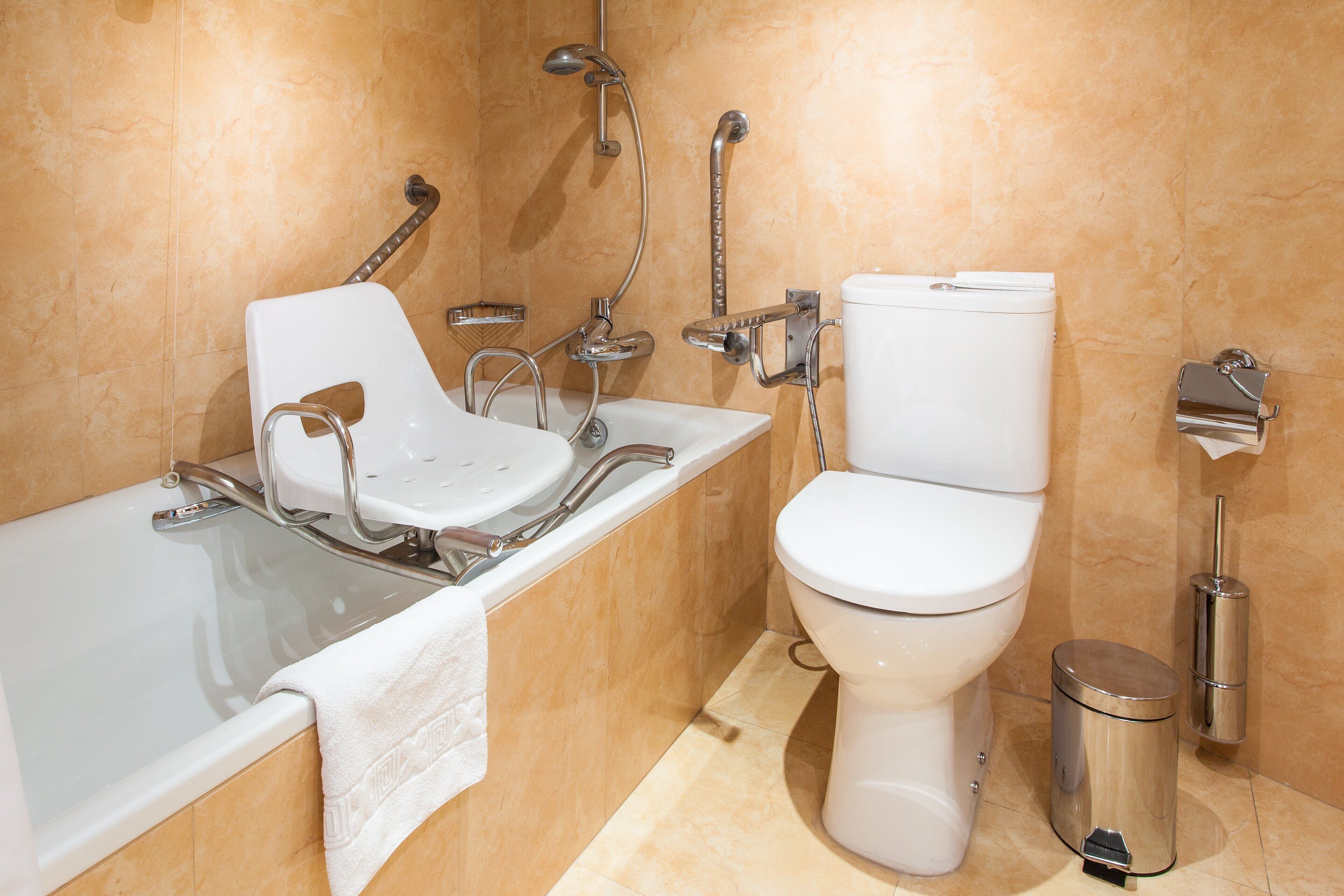 Un baño moderno con una bañera blanca, un inodoro y ducha de mano.