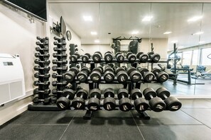 A gym with multiple rows of dumbbells, a TV mounted on the wall, and a large mirror reflecting the equipment. - Holiday Inn Lisbon Continental by IHG (Lisbon)