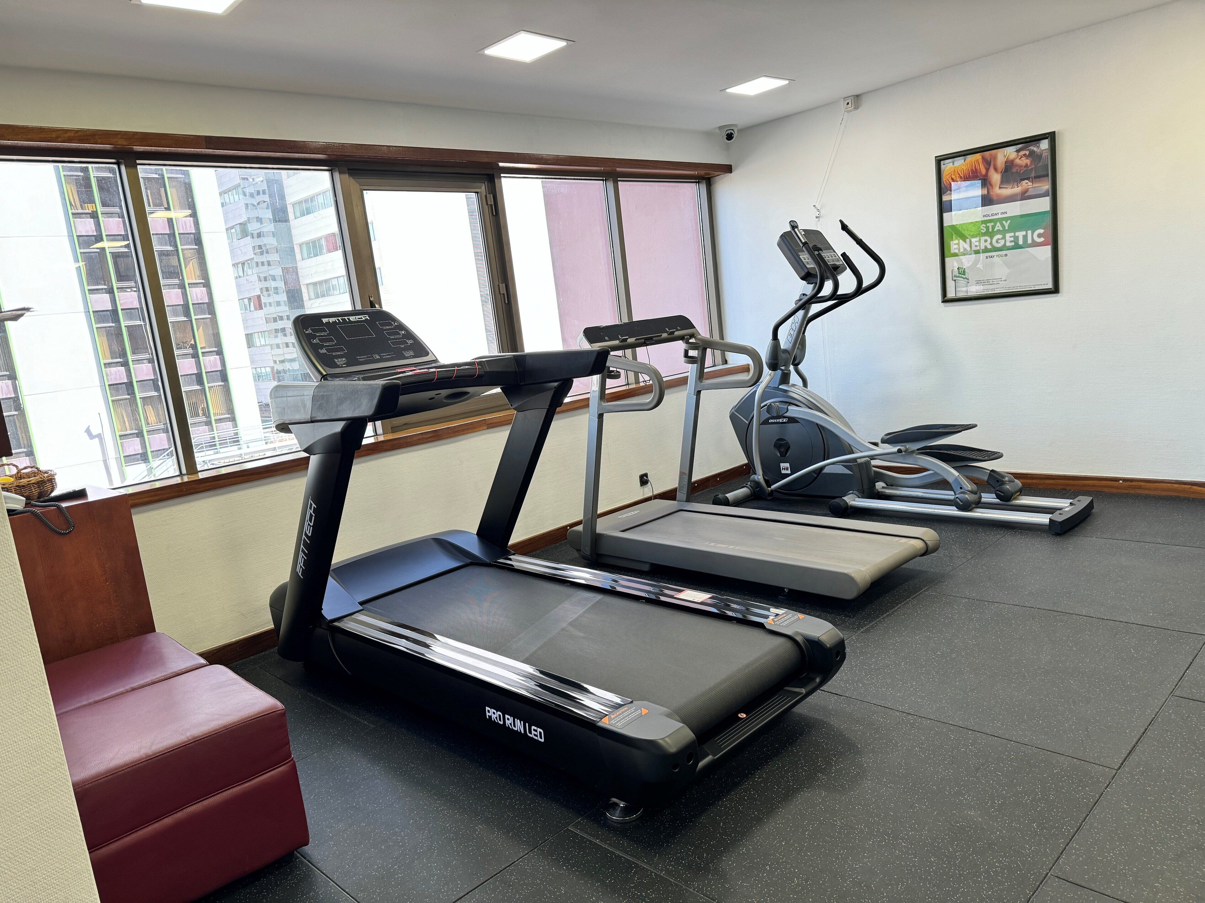 A gym with treadmills, an elliptical, and a red bench.