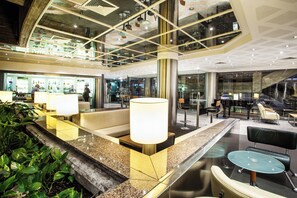 A hotel lobby with a reception desk, seating area, and a grand piano. - Holiday Inn Lisbon Continental by IHG (Lisbon)