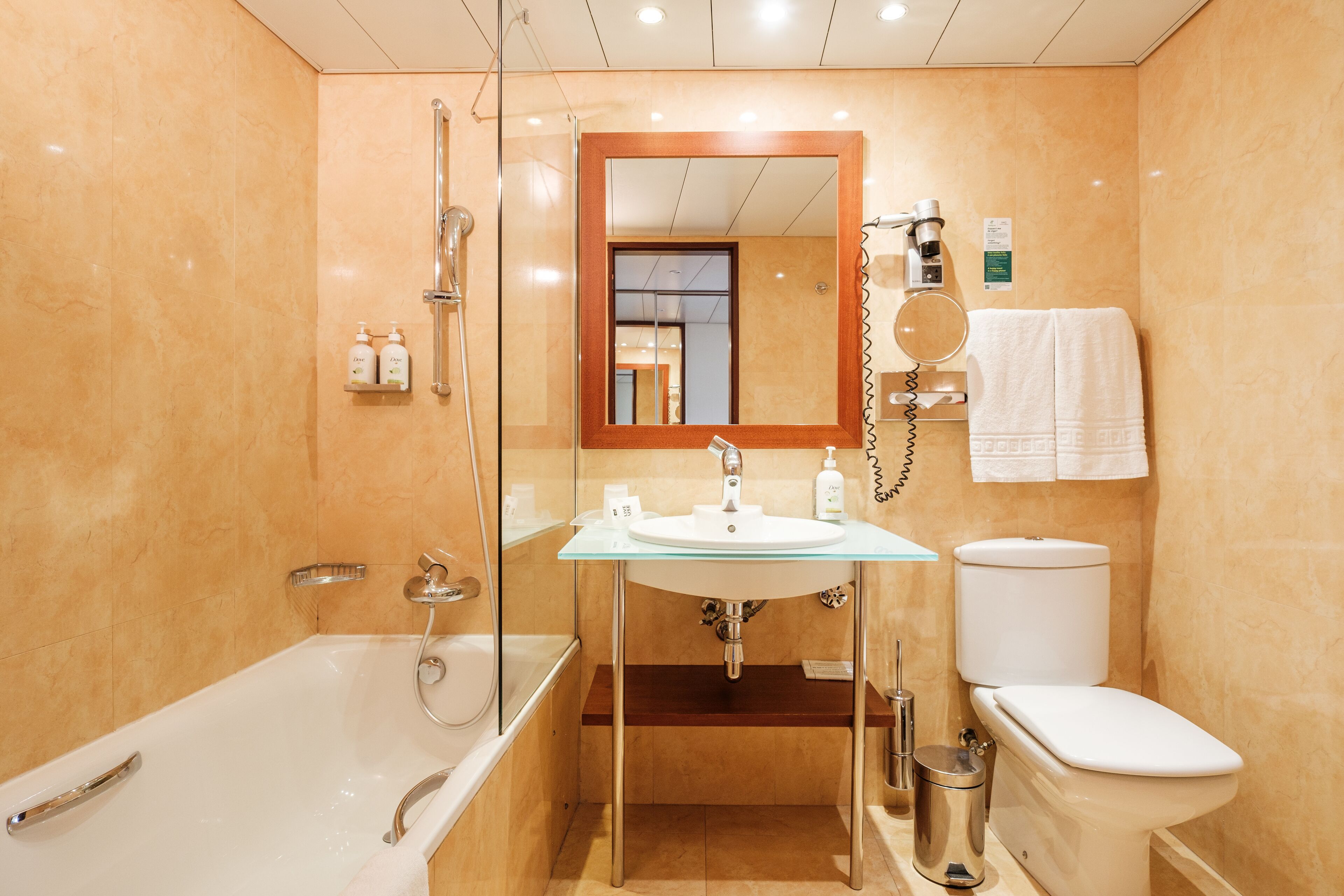 Un baño moderno con ducha envuelta en vidrio, un lavamanos blanco y un inodoro.