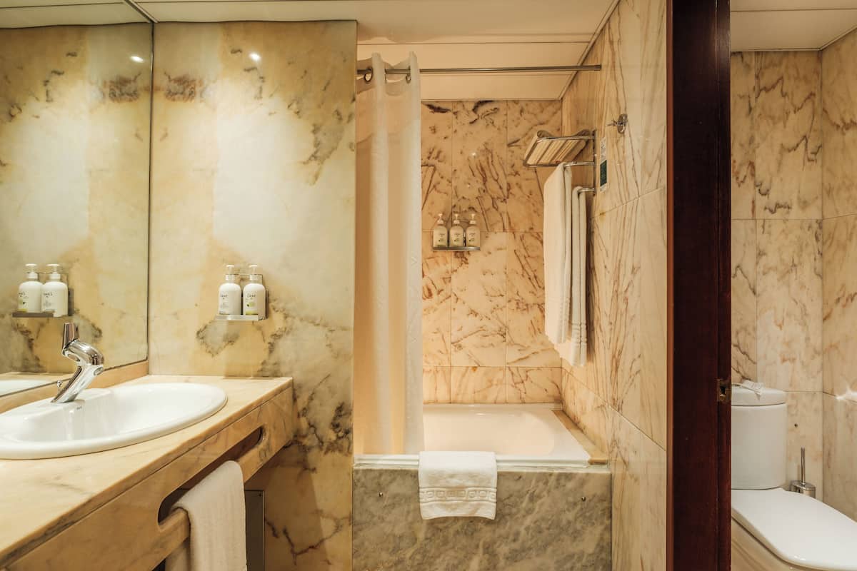A bathroom with a marble sink, a bathtub, and a toilet.