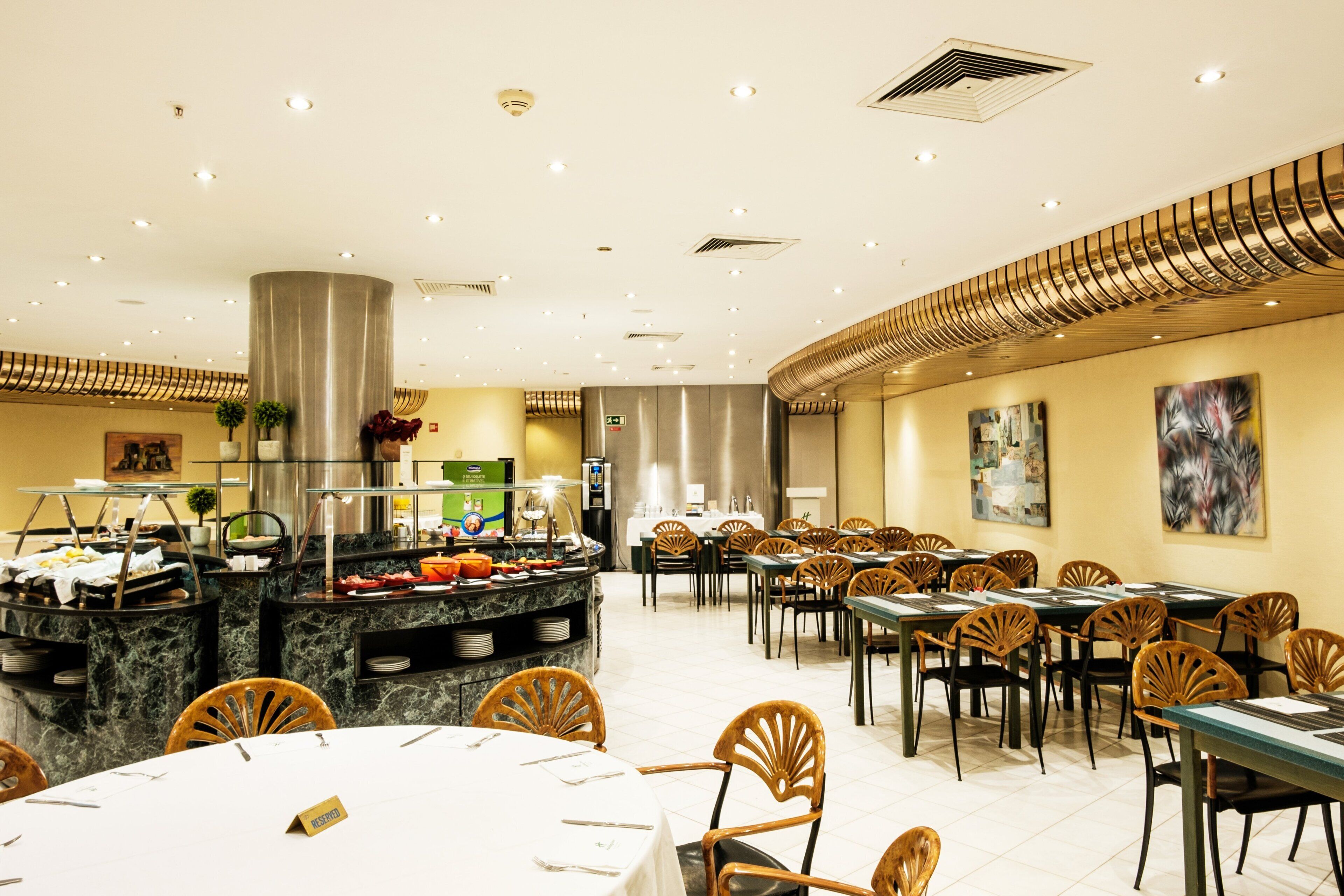 A spacious dining area with multiple tables and chairs, a buffet counter, and a modern ceiling design.